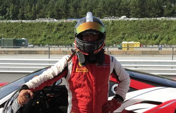 A racing driver standing next to a Ferrari car