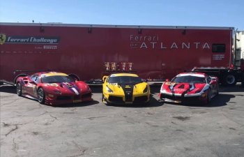 Three Ferrari cars standing next to a car transporter trailer
